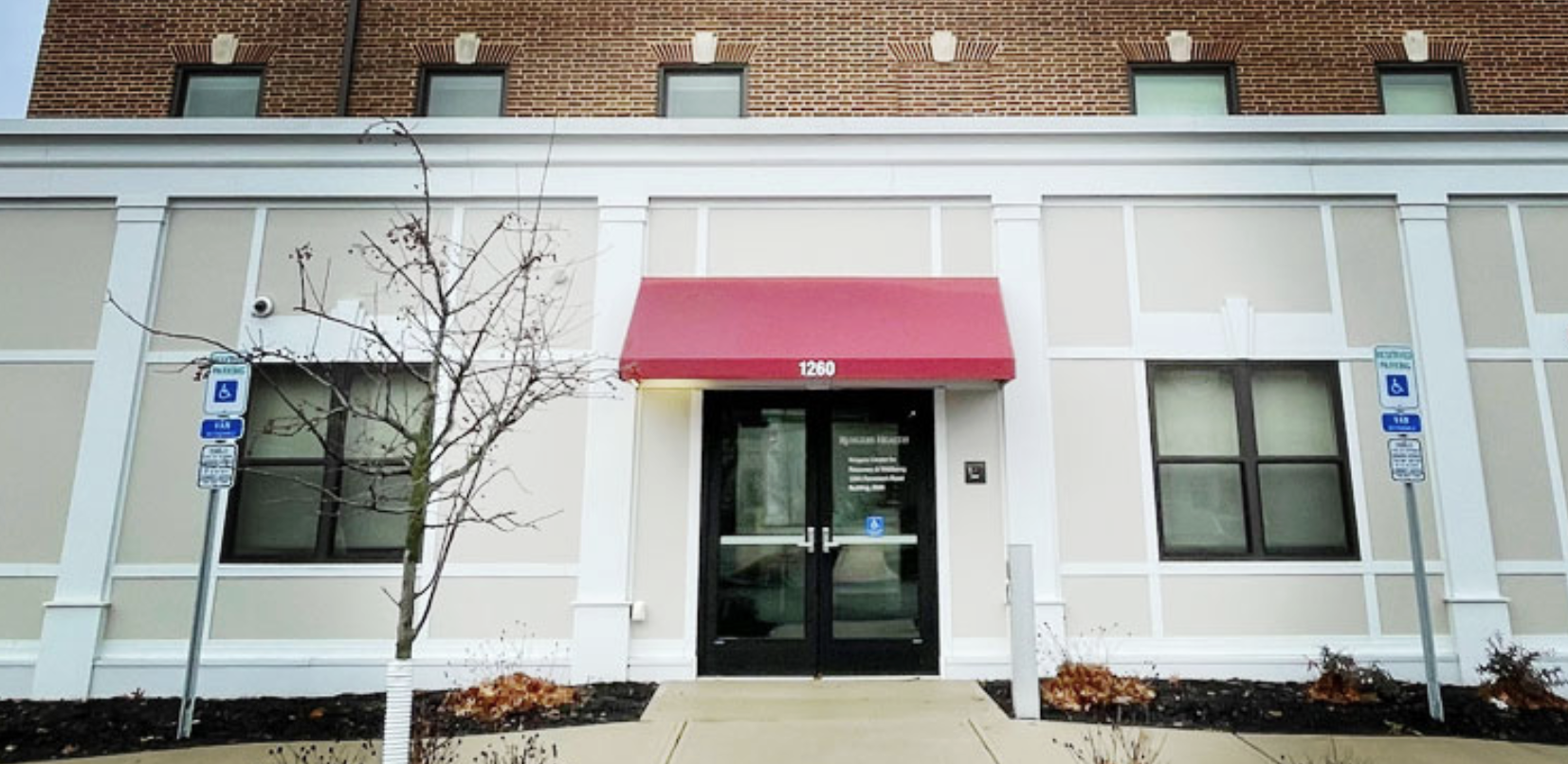 Entrance to a Rutgers University Behavioral Health Care outpatient facility with accessible parking and a red awning above the doors.